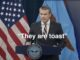 Speaker in suit before American flag, captioned