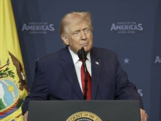 Older man at podium with yellow flag backdrop