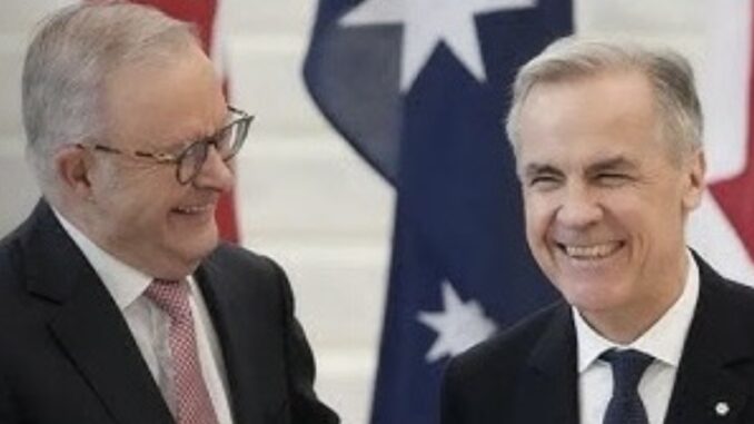 Two men in suits smiling beside national flags Two men in suits smiling beside national flags