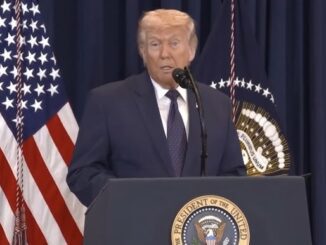 Man speaking at podium with American flag.