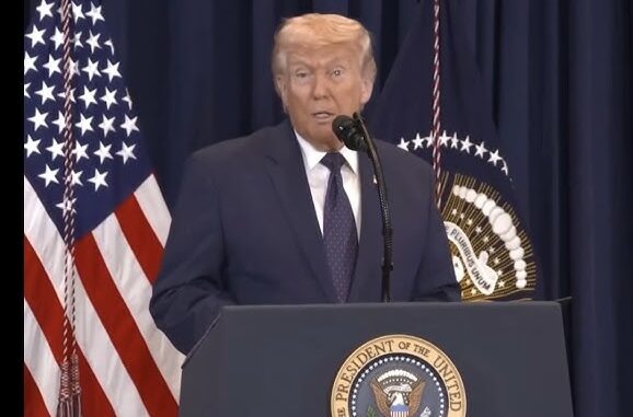 Man speaking at podium with American flag. Man speaking at podium with American flag.