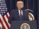 Man speaking at podium with American flag.
