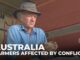 Farmer examining grain, conflict impact highlighted.