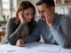 Couple worriedly looking at financial documents.