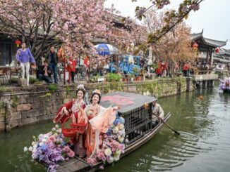 Women in traditional attire on flower boat.