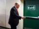 Man opening a green exit door.
