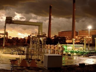 Industrial facility at sunset with smokestacks.