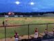 Night baseball game under bright stadium lights.