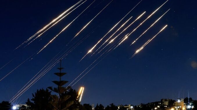 Lights streaking across night sky over city.