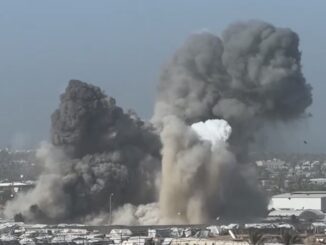Large explosion with billowing smoke over buildings.