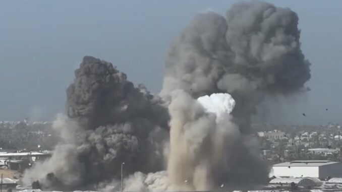 Large explosion with billowing smoke over buildings.