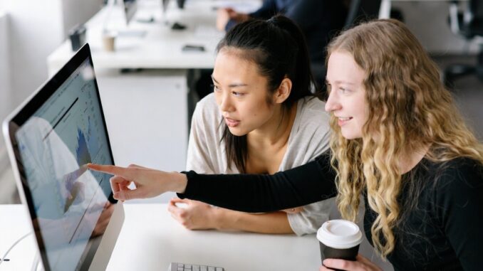 Two women collaborating at a computer screen. Two women collaborating at a computer screen.