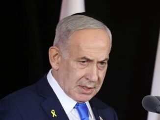 Elderly man speaking at podium with yellow ribbon