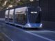 Futuristic metro bus on a quiet road.