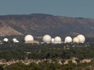 White radar domes lined beneath distant mountains