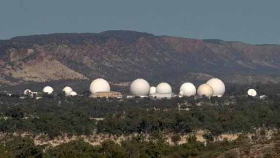 White radar domes lined beneath distant mountains