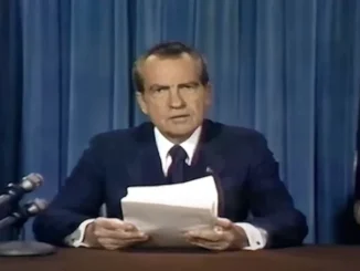 Man reading papers at podium with microphones