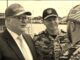 Three smiling naval officers conversing at dock