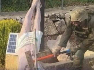 Soldier in combat gear smashing device with sledgehammer