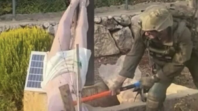 Soldier in combat gear smashing device with sledgehammer