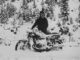 Person on snow-covered motorcycle in snowy forest