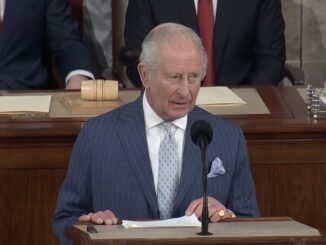 Elderly man in pinstripe suit speaking at podium