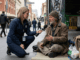 Reporter interviewing man on city sidewalk