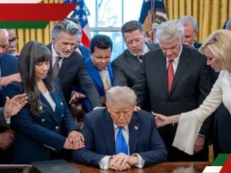 People praying around seated man at desk