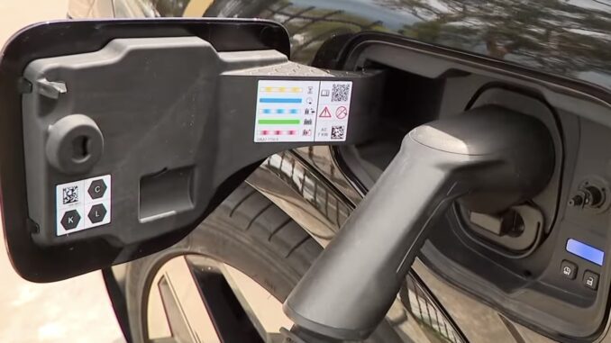 Electric car charging plug connected to vehicle