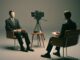 Two faceless figures in staged interview setting