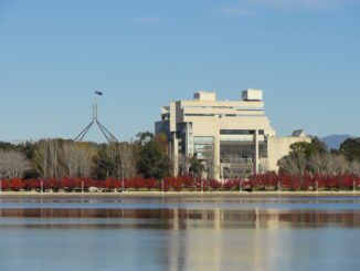 Government building and flag reflected in lake