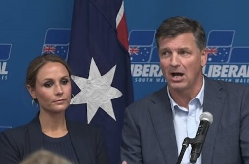 Two people speaking at press conference with flag Two people speaking at press conference with flag