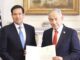 Two men in suits holding official document
