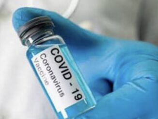 Gloved hand holding COVID-19 vaccine vial