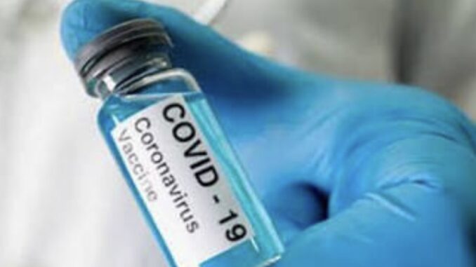 Gloved hand holding COVID-19 vaccine vial