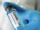 Gloved hand holding COVID-19 vaccine vial