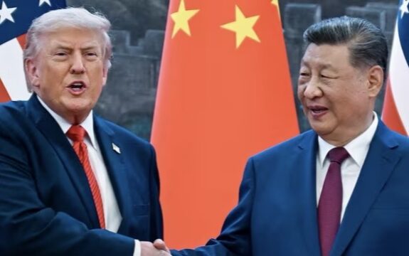 Two people shaking hands before national flags