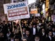 Crowd protest with sign reading "ZIONISM