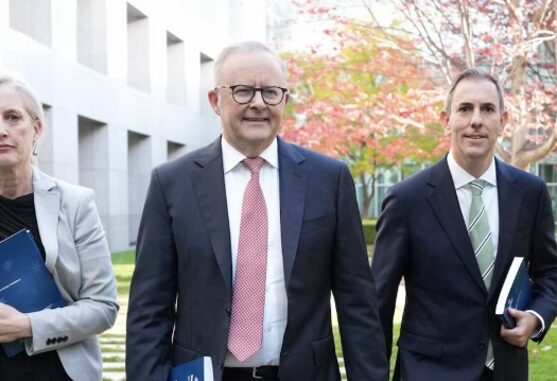 Three professionals walking outdoors holding folders