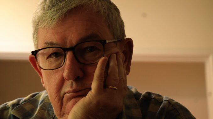 Pensive older man with glasses resting chin