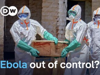 Healthcare workers in hazmat suits carrying coffin
