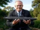 Man in suit holding submarine model