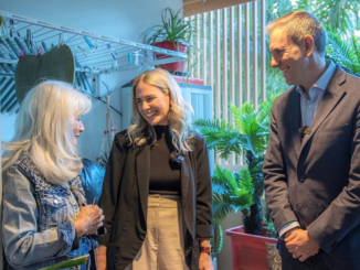 Three people smiling amid indoor plants