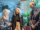 Three people smiling amid indoor plants