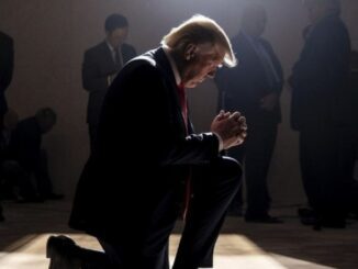 Person kneeling in spotlight with clasped hands