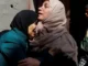 Two women embracing in grief, boy nearby