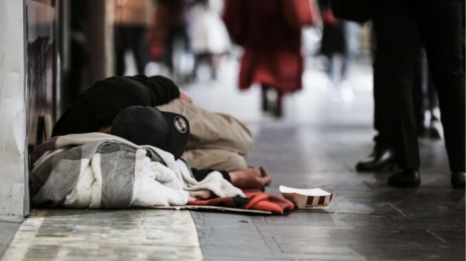 Homeless person sleeping on city sidewalk