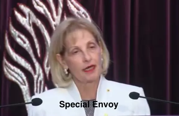 Woman speaking at podium captioned "Special Envoy