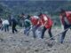 Group of volunteers tilling soil in rural field