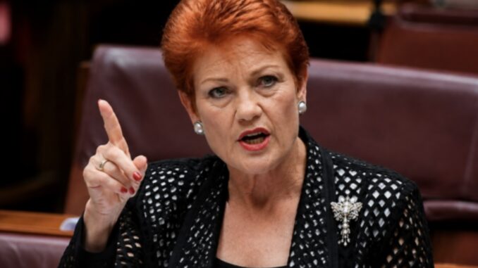 Red-haired woman pointing while speaking in chamber